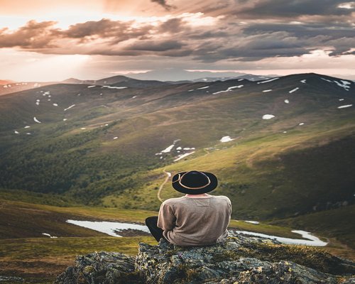 Man sitting on a mountain enjoying peaceful sunset lifestyle